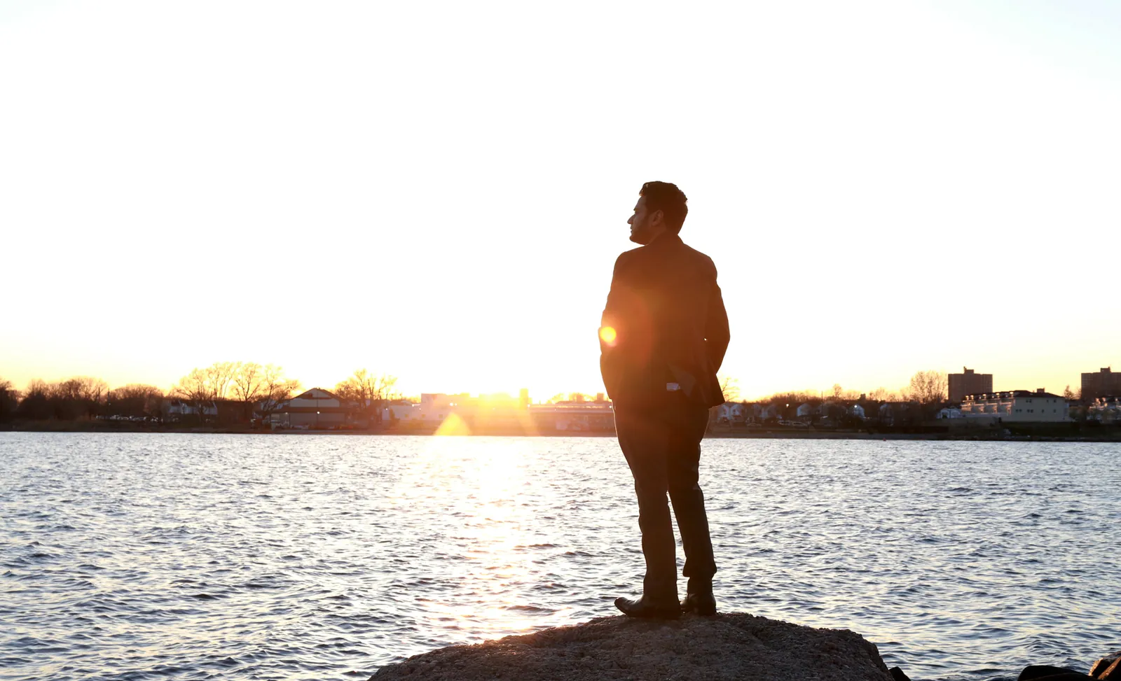 Iqbal HJ standing by the water at sunset